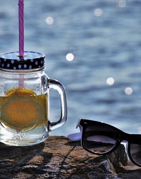 bocal boisson citron lunettes de soleil sur rocher en bord de mer