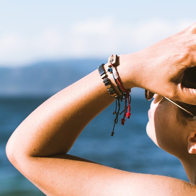 bronzage femme bronzée qui se passe la main dans les cheveux l'été